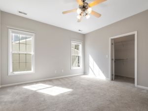 Empty room with beige carpet and sunlight entering through windows, highlighting potential carpet fading issues.