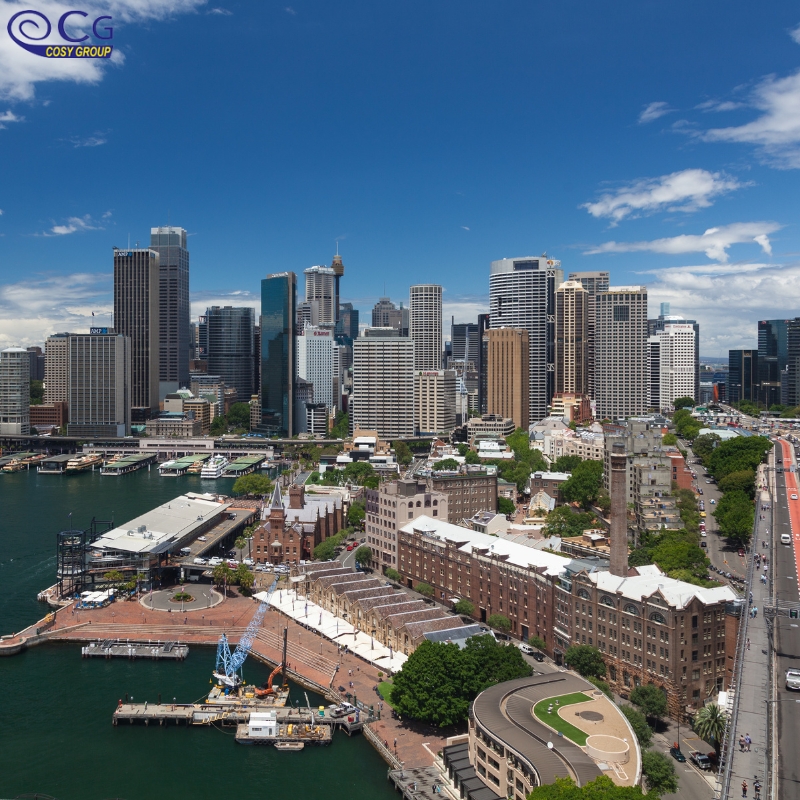 A panoramic view of a bustling city skyline with tall buildings and harbor in the foreground.